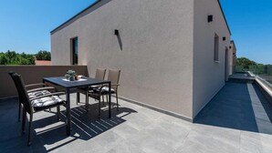 Eine moderne Außenpatio mit Tisch, Stühlen, einem kleinen Topfpflanzen und freiem Blick zum Himmel.