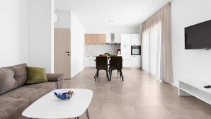 Ein modernes Wohnzimmer mit einer Couch, einem Couchtisch und einem Essbereich mit zwei Stühlen.
