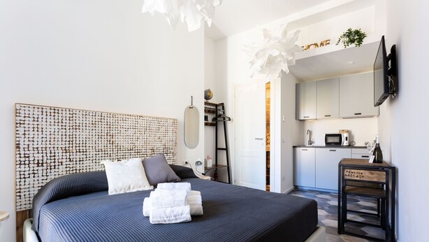 Un dormitorio moderno con una cama grande, una mesita de noche y vistas a la cocina.