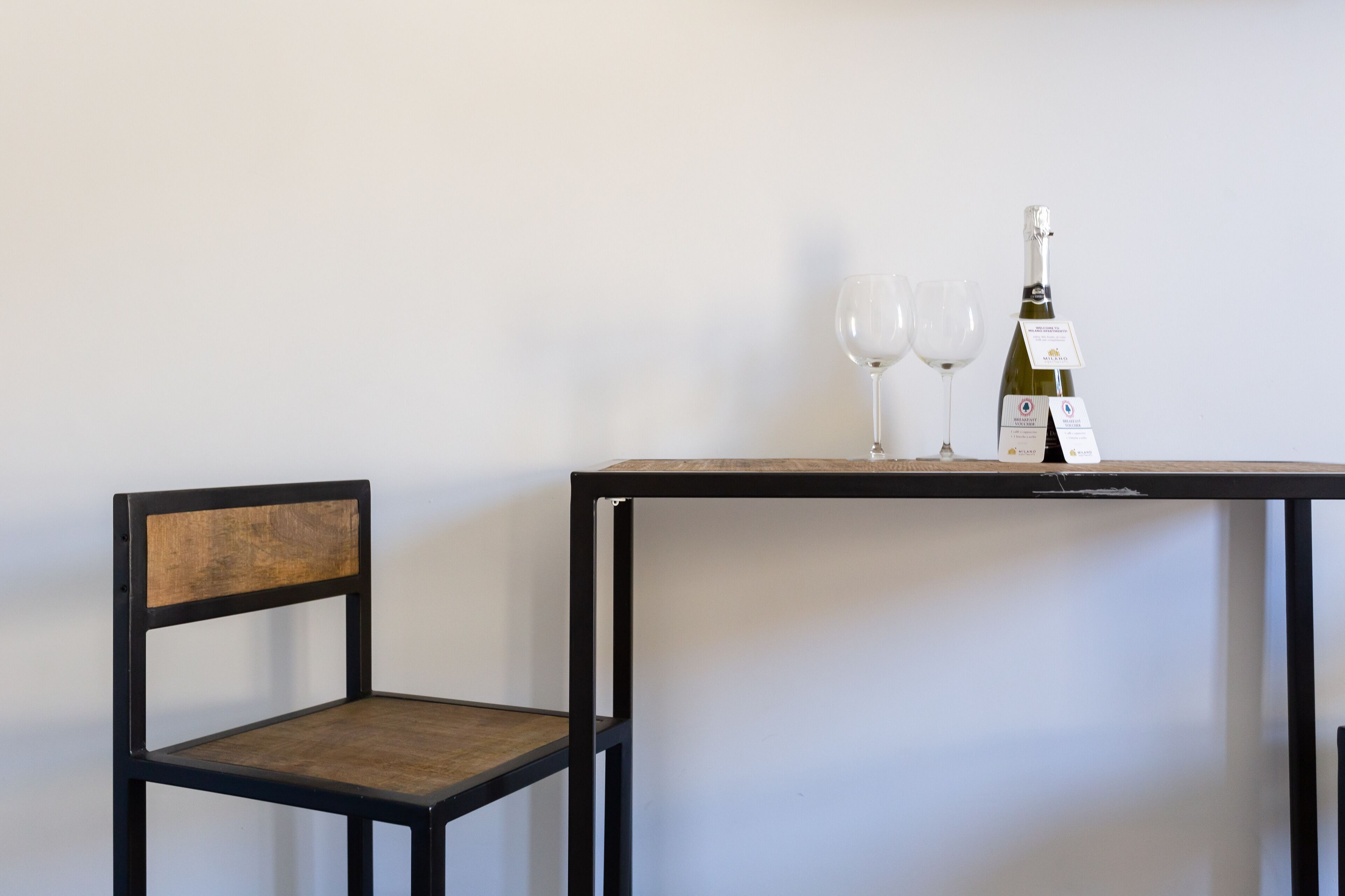 Une chaise et une table avec deux verres à vin et une bouteille de vin.
