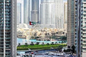 A high-rise building with a view of a swimming pool and palm trees. - Stayis - 1 BR Iconic Burj Khalifa View (Dubai)