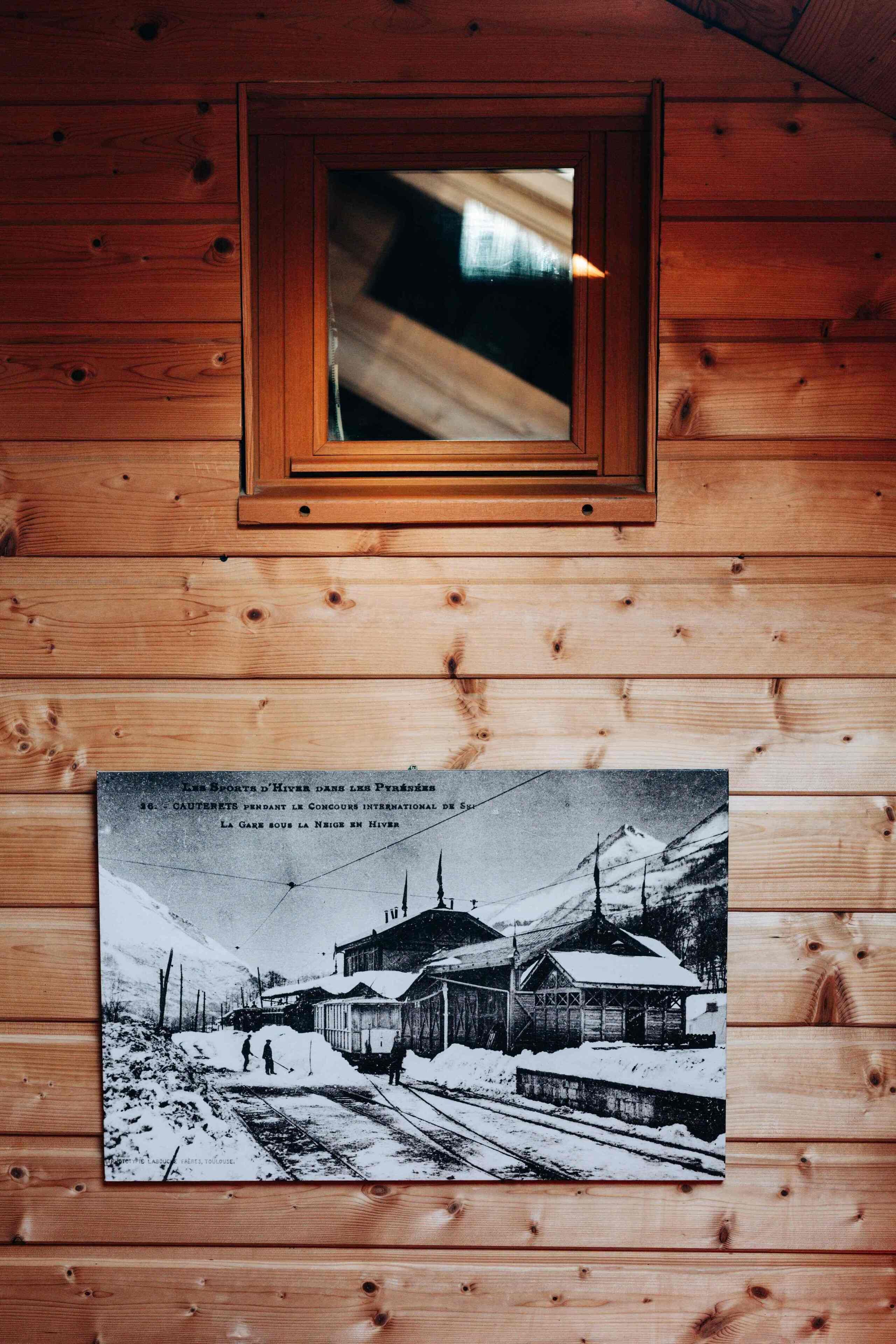 Ein Holzhütten-Interieur mit einem gerahmten Foto von einem verschneiten Bahnhof.