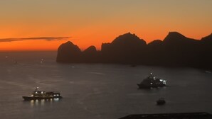 A sunset over a body of water with boats and a mountainous coastline. - Corazón Resort&Spa: 2BR Corazon Suite w/ private hot tub, ocean view, sleeps 8 (Cabo San Lucas)