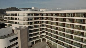 A multi-story hotel with a modern design, featuring balconies with furniture and a central courtyard. - Corazón Resort&Spa: 2BR Corazon Suite w/ private hot tub, ocean view, sleeps 8 (Cabo San Lucas)