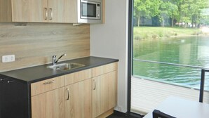 Cuina moderna amb armaris de fusta, un microones d'acer inoxidable i una finestra gran amb vista a un llac.