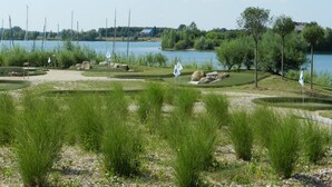 Camp de golf amb búnquers, senyeres i un llac al fons.