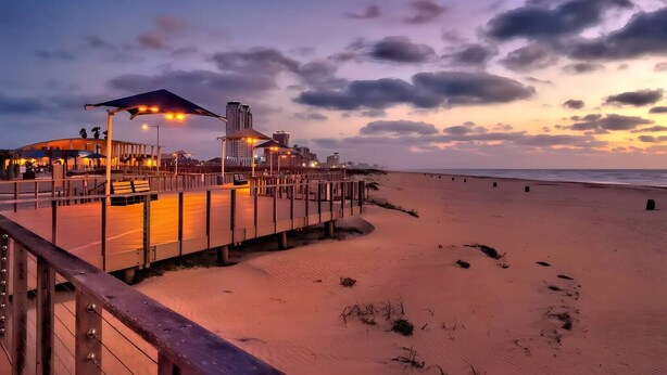 A beachside promenade with a wooden walkway, a covered seating area, and a view of the ocean. - Experience coastal luxury at Sunny Isle Sanctuary. This chic 2BR/2BA features a designer kitchen, private bay-view balcony, and modern finishes. Reliable service meets the comfort of home. Perfect for your high-end SPI getaway. Book your stay now! (South Padre Island)