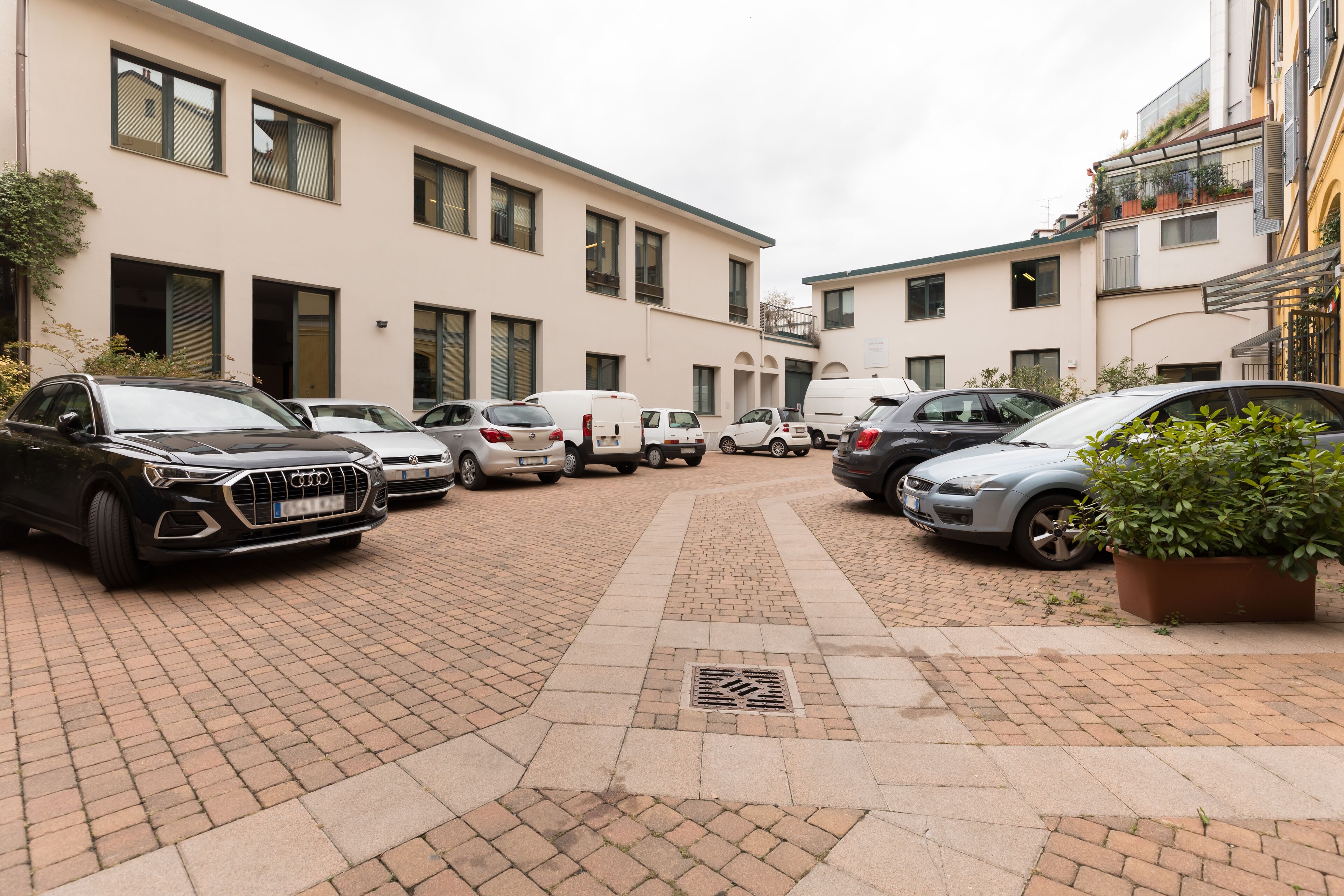 A parking area with multiple cars and a building with large windows and a flat roof.