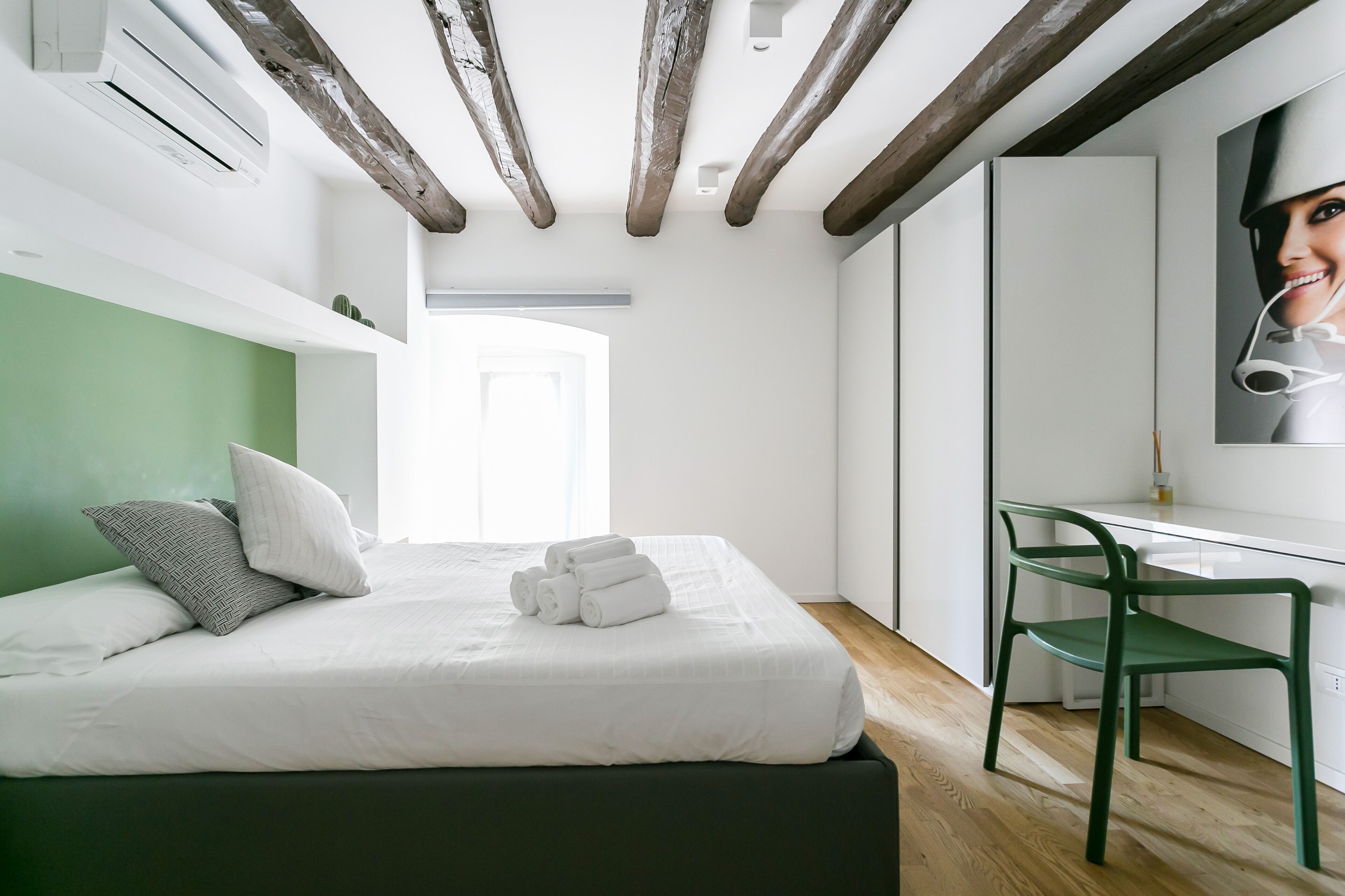 Une chambre à coucher moderne avec un lit, des oreillers, un bureau et une chaise.