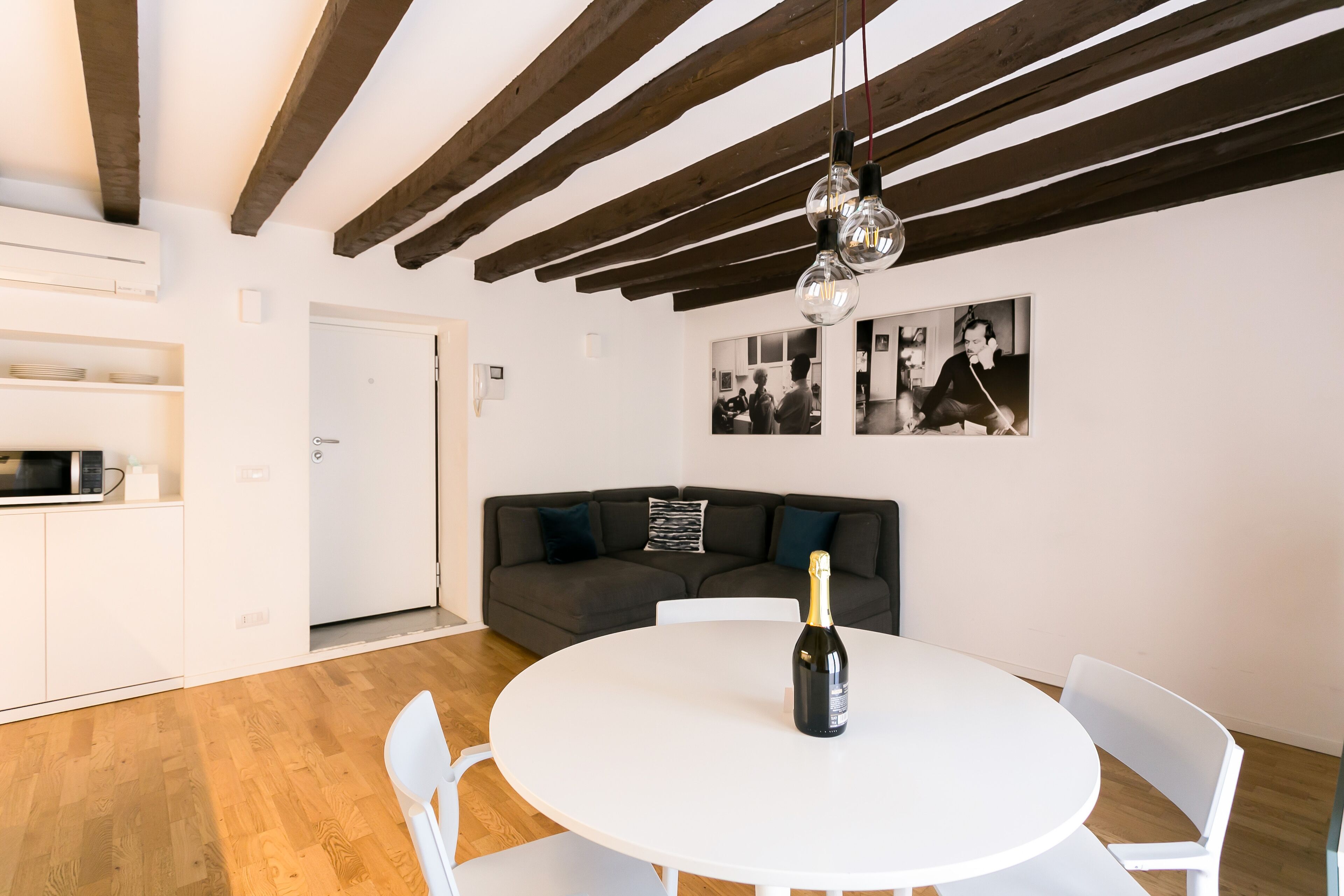 A modern living room with a white round table, a dark grey sofa, and a wooden ceiling.