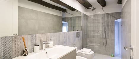 A modern bathroom with a large sink, toilet, and shower area.