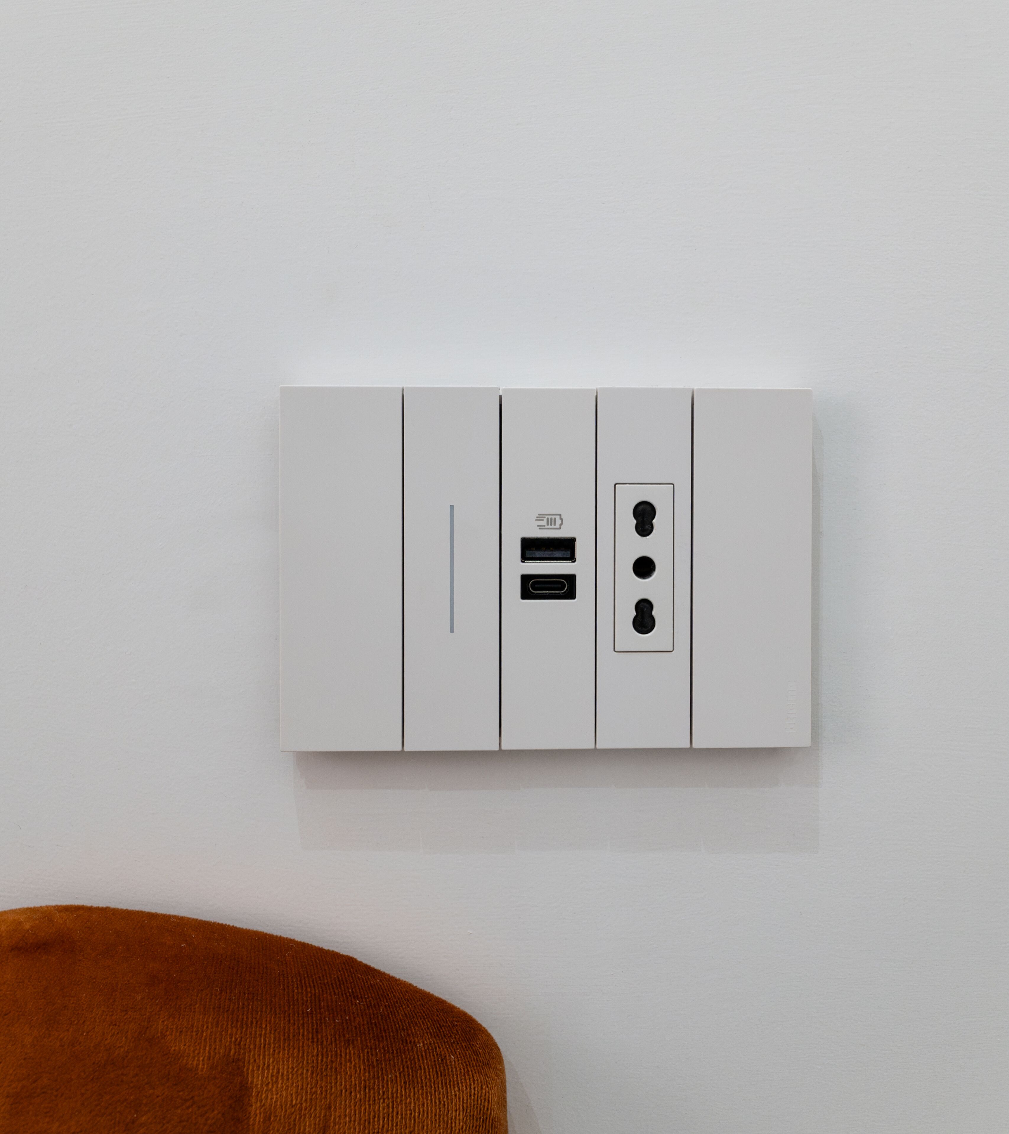 A white electrical panel with a USB port, a power outlet, and a switch on a plain wall.