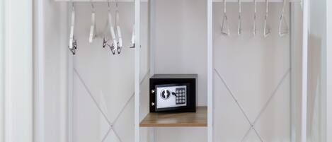 A white metal wardrobe with a microwave on the top shelf, wooden shelves, and a hanging rack.