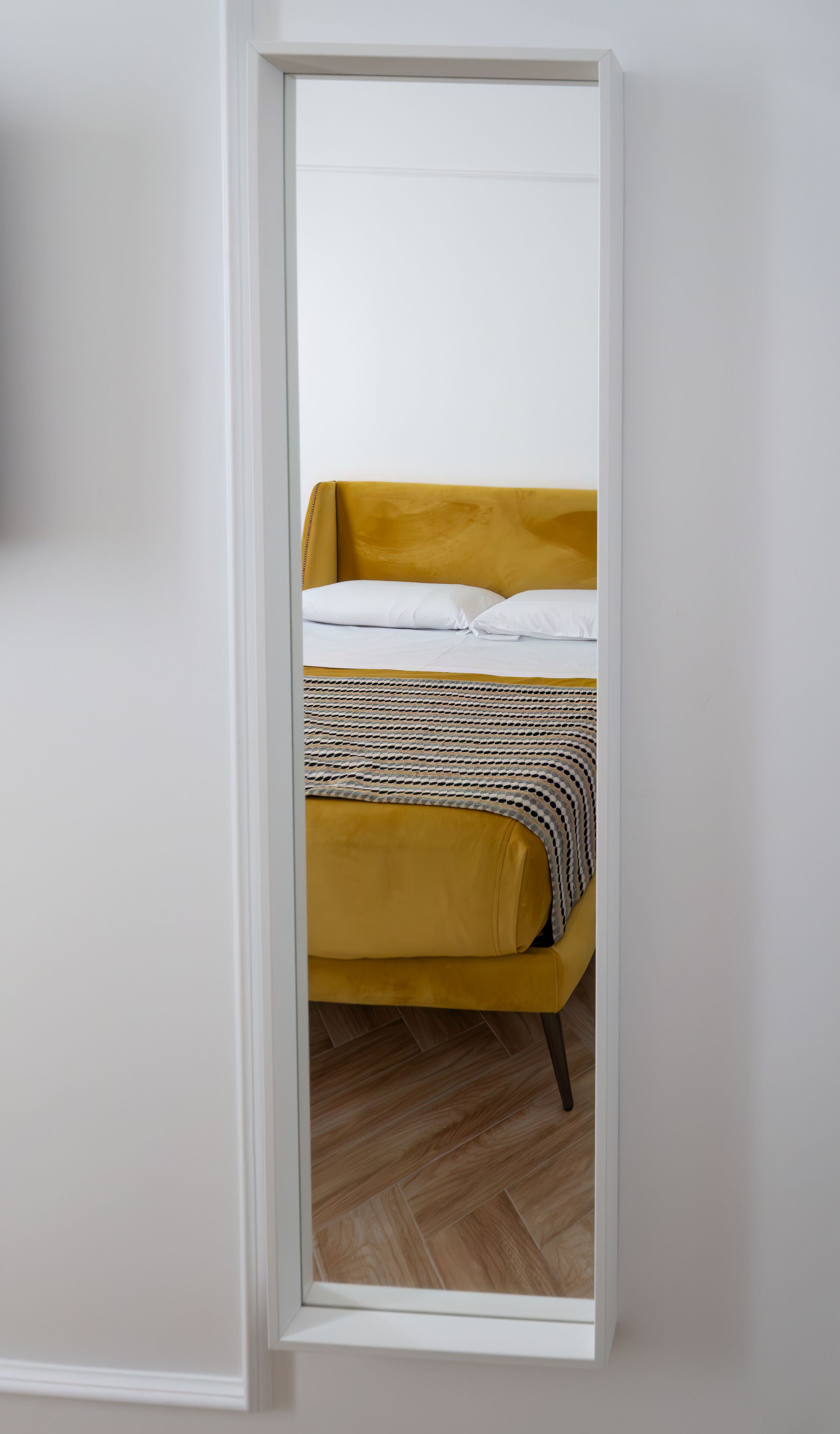 A room with a bed, a white door, and a wooden floor.