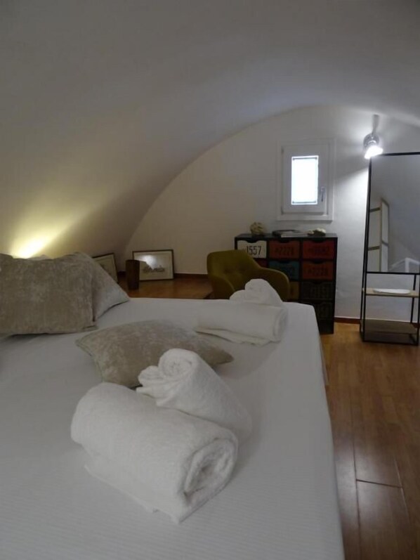A bedroom with a large bed, a dresser, a chair, and a small window. - LA DIMORA DELLE 3 ZIE (Matera)