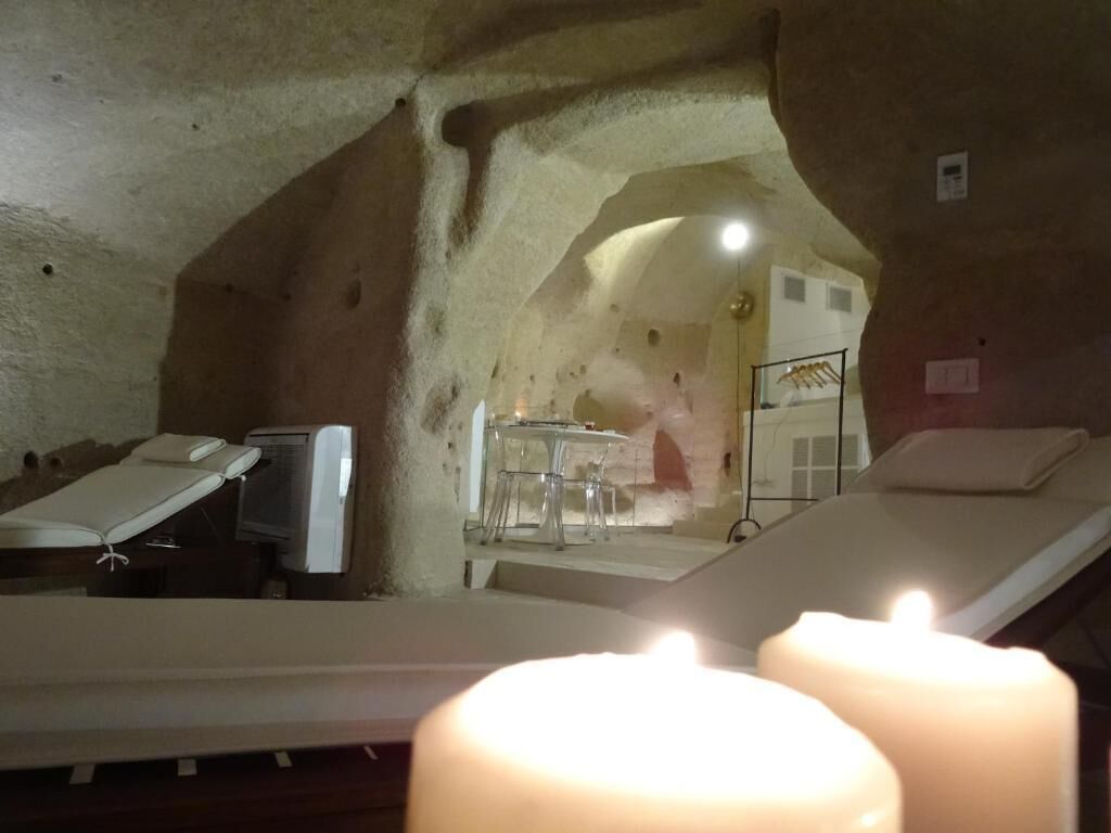 Una stanza spa con lettino da massaggio, poltrona massaggiante e un tavolino con una sedia.
