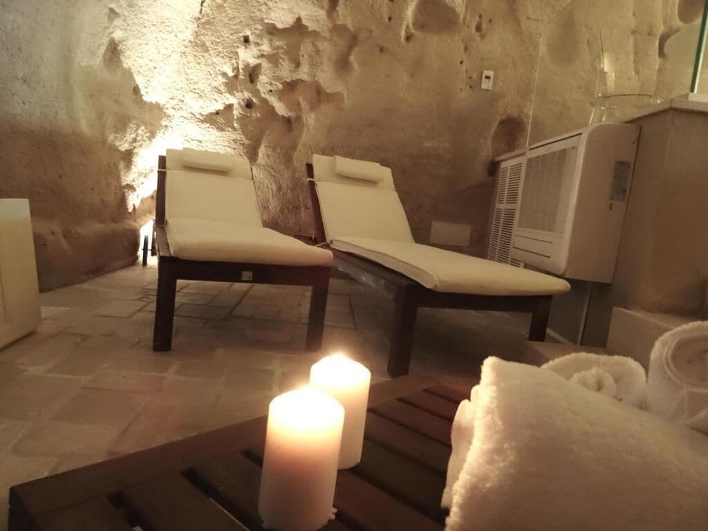 A spa room with two lounge chairs, a table with candles, and a towel rack.