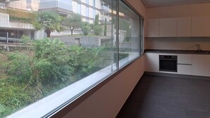 Eine moderne Küche mit großem Fenster, einem Geschirrspüler und Blick auf eine Wohngegend mit Grünflächen und Gebäuden.
