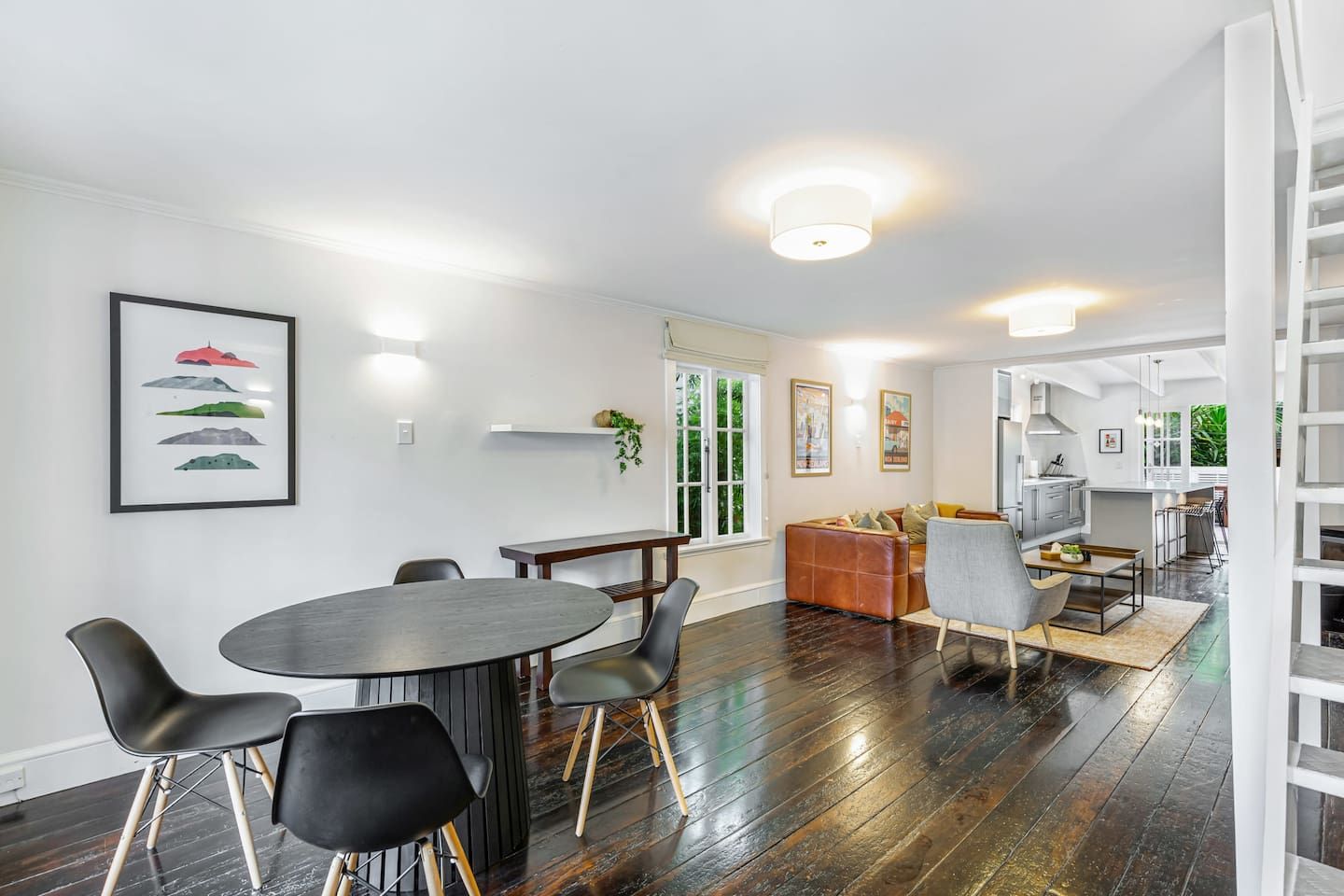A modern interior with a dining area, kitchen, and a staircase.