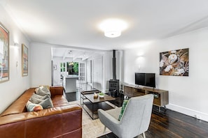 Ein modernes Wohnzimmer mit einer Ledersofa, einem grauen Sessel, einem Couchtisch, einem Fernseher und einem Kamin.