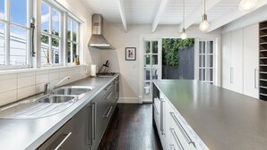 Una cocina moderna con electrodomésticos de acero inoxidable, armarios blancos y ventanas amplias.