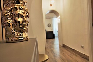 Een gang met een gouden sculptuur, houten vloer en een klok aan de muur.