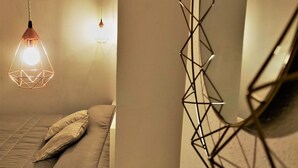 A bedroom with a bed, pillows, and a hanging light fixture. - Athena Apartment Ortigia Holidays (Siracusa)