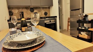 Une cuisine moderne avec une table à manger pour deux personnes, agrémentée d’une assiette décorative et de deux verres à vin.