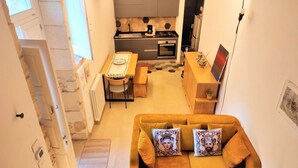 Un espace de vie compact comprenant un canapé, une table à manger et un coin cuisine.