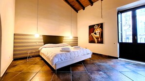 Un dormitorio con cama, cabecero, un cuadro y una ventana.