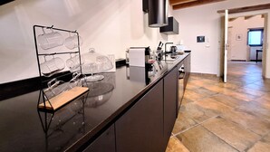 Una cocina moderna con encimera negra, vitrina de vidrio y estante de madera.