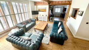 A spacious living room with a fireplace, two sofas, a coffee table, and a TV. - The Cart Lodge at Lee Wick Farm Cottages (Clacton on Sea)