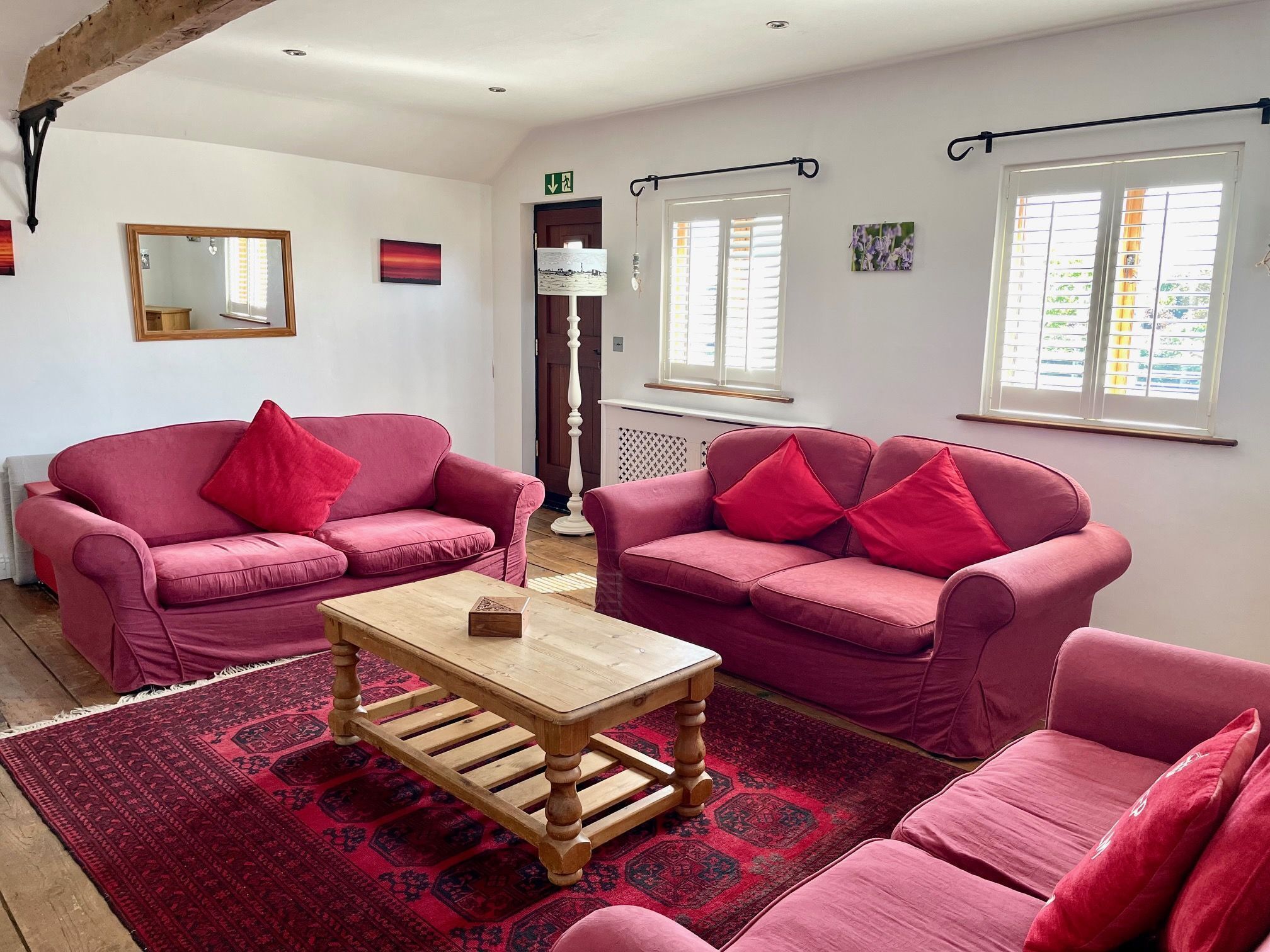 A room with two pink sofas, a wooden coffee table, a patterned rug, and a mirror on the wall.