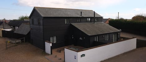 A two-story building with a sloped roof, a small porch, and a sign that reads "Welcome".