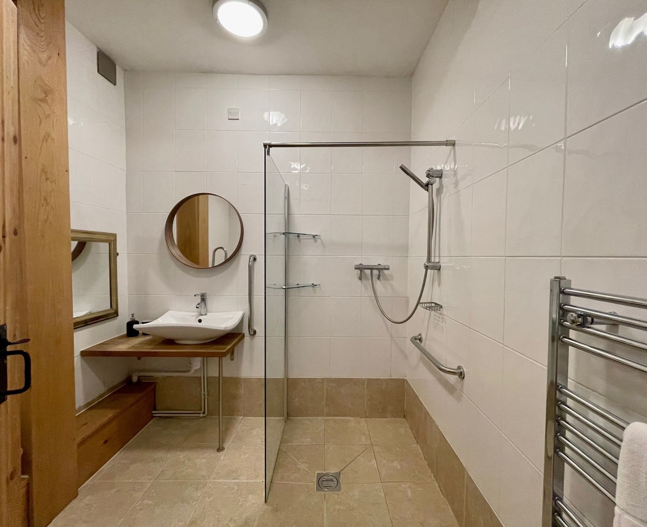 Ein Badezimmer mit Waschbecken, Spiegel, Dusche und Handtuchhalter.