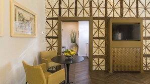 A room with a dining table, chairs, a TV, and a decorative wall. - Maisonnette V.V.155 Ortigia Holidays (Siracusa)