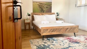 A bedroom with a wooden bed, a nightstand, a lamp, and a large window.