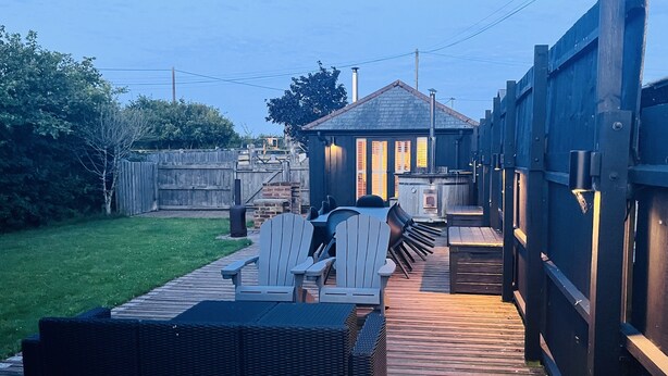 A wooden deck with outdoor furniture, a hot tub, and a barbecue area.