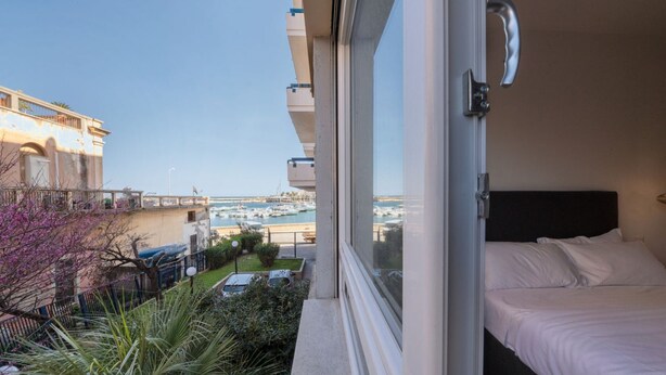 Ein Balkon mit einem Bett, Blick auf den Yachthafen und ein Gebäude mit Balkon.