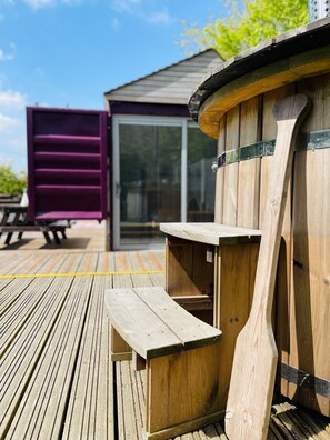 Une terrasse en bois avec une table de pique-nique et une structure en forme de tonneau en bois.