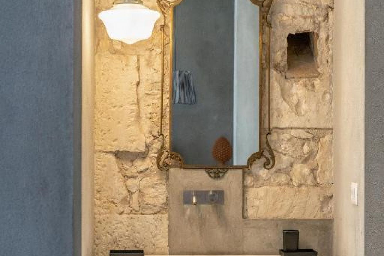 Een badkamer met een stenen muur, een spiegel en een handdoek aan de muur.