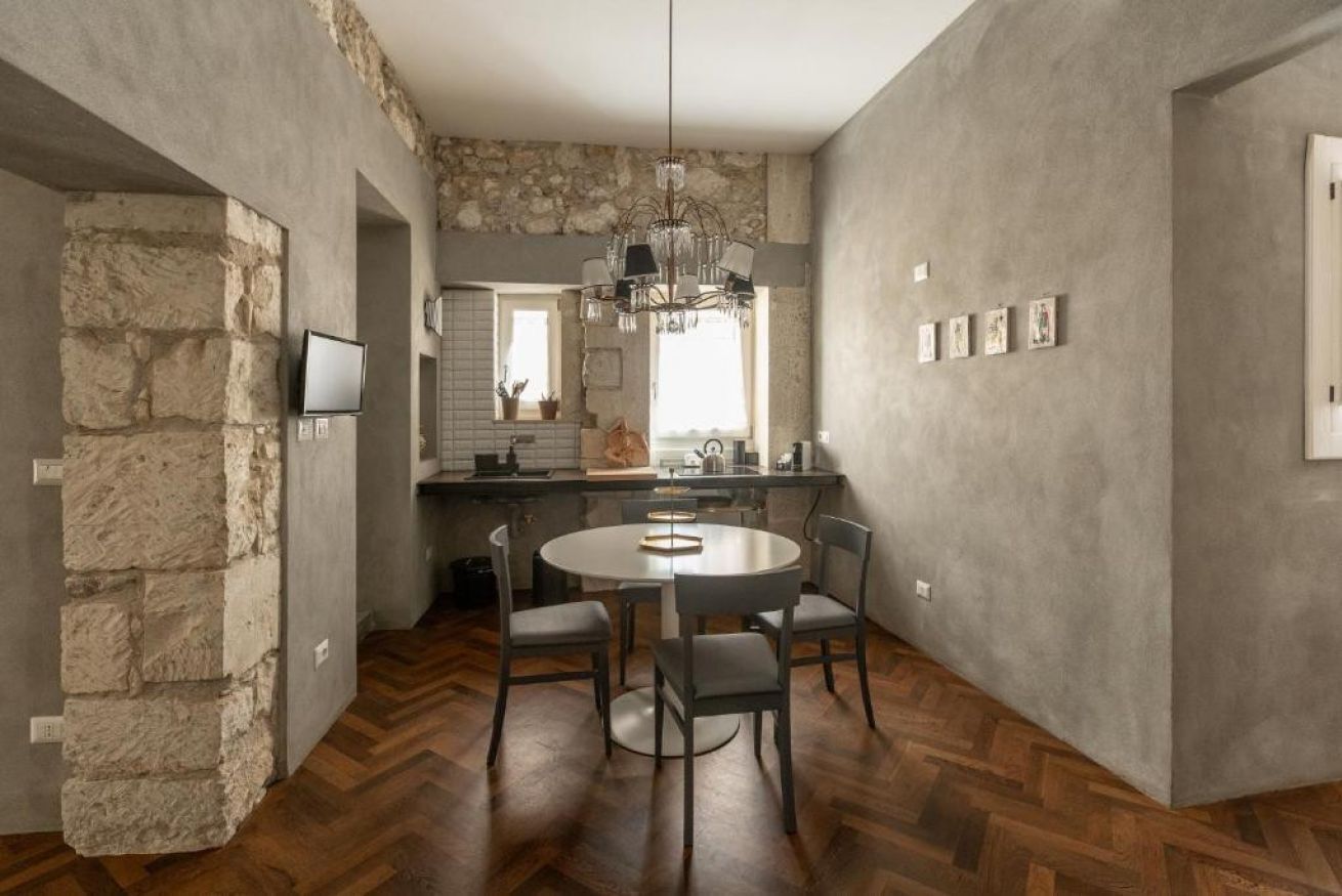 A modern kitchen with a stone accent wall, a chandelier, and a round dining table with chairs.
