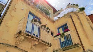 Ein Gebäude mit mehreren Balkonen, von denen einige mit Pflanzen und Blumen bepflanzt sind, im traditionellen Baustil.