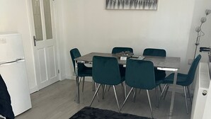 Une cuisine compacte avec un coin repas, comprenant un réfrigérateur, une table à manger avec des chaises et un tapis noir.