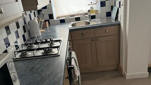 Une cuisine équipée d’une cuisinière à gaz, d’un évier et de meubles de rangement en bois.