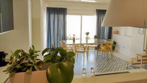 Ein moderner Essbereich mit Glastisch und Stühlen, einer großen Lampe und einem Blumentopf.