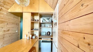 Una cocina compacta con paredes de madera y un estante para microondas integrado.