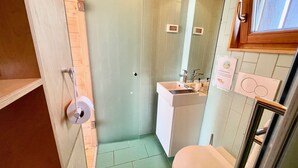 A small bathroom with a toilet, sink, and mirror. There is a wooden door and a window above the sink. - Lushna Petite 3 at Lee Wick Farm Glamping (Clacton on Sea)