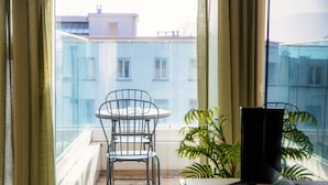Un balcon avec une table et des chaises, une plante en pot et un téléviseur.