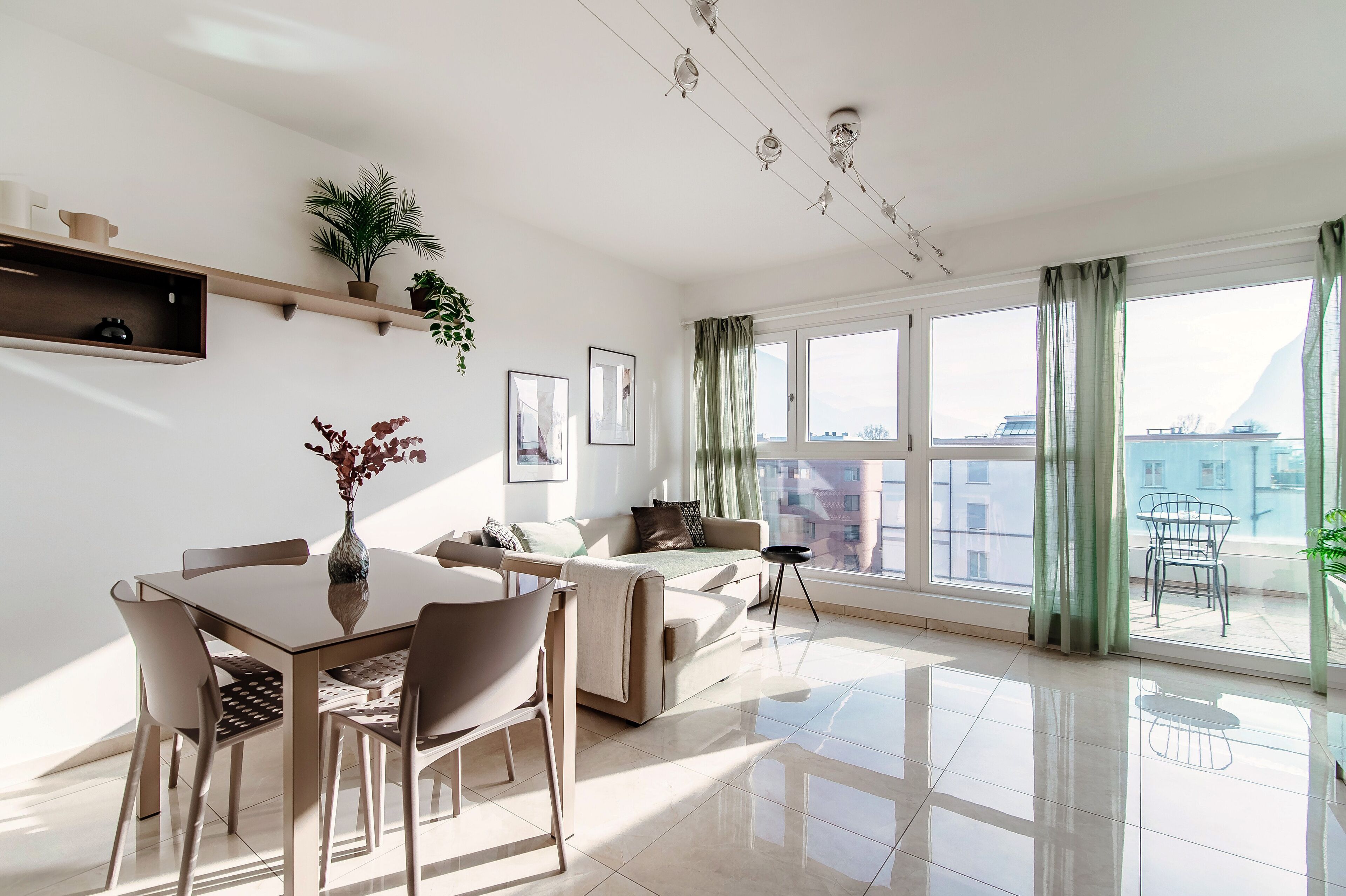 Una sala de estar moderna con comedor, ventanas amplias y vista a la ciudad.